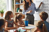 A teacher teaching some new words written on a board to a group of kids.