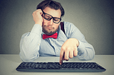 Employee tiredly clicking keys on a keyboard.