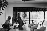 A picture of Geoffrey Bawa sitting in his tropical modernist fashioned office and the courtyard area is visible in this image.