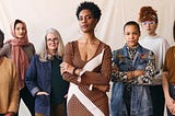 Group of diverse women standing confidently together against a neutral background, representing leadership, clarity, and collective strength in design and tech.