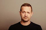 Man in a black t-shirt looking comically pensive
