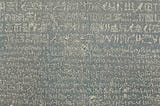 The Rosetta Stone, an ancient Egyptian artifact, featuring inscriptions in three scripts: hieroglyphic, demotic, and Greek. This stone was crucial in deciphering Egyptian hieroglyphs, as scholars could compare the identical text across the three scripts to unlock their meaning.