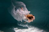 Young woman posing submerged underwater in a flowy dress
