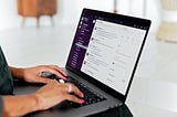 Woman typing on a laptop with Slack desktop on the screen.