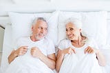 A mature couple in bed and pleased with themselves.