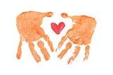 On a white background, two orange prints of a child’s hand encircle a painted red heart