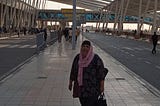 The blogger wearing grey joggers, a black and pink floral top and pink hijab standing outside the arrival hall at Cairo International Airport