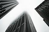 Tall buildings rise into the sky. Black-and-white photo.