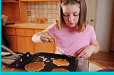 Child making pancakes in a kitchen