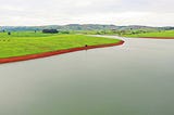 Greenfield beside a body of water in Northern Nigeria. Photo by Oshomah Abubakar on Unsplash