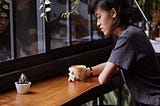 woman sitting alone at a table, drinking coffee