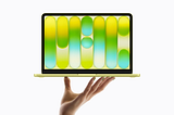 A hand holding up the all-new MacBook Neo