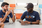 Group of students wearing ASAP t-shirts sit around a table.