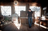 Gentry Bronson standing in front of an upright piano in Tomales Bay, California
