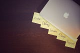 Macbook with post it notes stating phrases, “code, debug, learn, sleep, repeat”