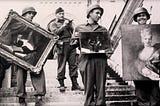 Four Monuments Men on the steps of a palace. Three are holding recovered artwork.