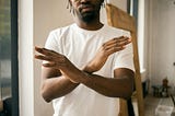 Faceless black man showing stop gesture with crossed hands