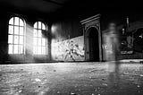 A photo of a large room, perhaps in an old school, were blurred images of beings are moving.