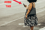 Woman in crosswalk looking at phone, about to be killed or cause an accident