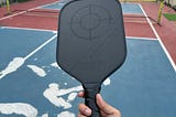 Holding a pickleball paddle at the outdoor pickleball court in Bangkok.