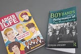 Two books side by side about Boy Bands. One is pink with cartoon pictures, the other is green with a picture of the Beatles