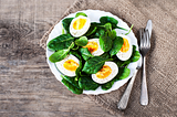 spinach and haled boiled eggs on a round white plate