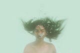 A woman breathing out under water