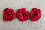 Three red crochet flowers