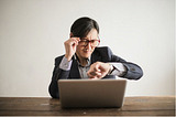 Lawyer looking on watch while working on laptop