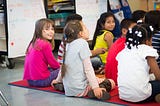 Elementary school children sitting on a rug