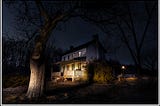 A farmhouse caught in the headlights of a car