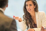 A woman dressed in business professional attire is in negotiations in a meeting room.