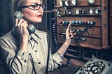 Old-style telephone operator sitting at a switchboard