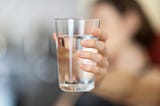 Person holding a clear glass of fresh water.