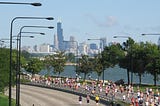 A photo of the Chicago Marathon showing runners on Lake Shore Drive with the downtown skyline in the background.