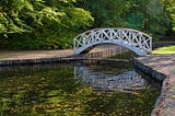 a small footbridge over a stream in a park