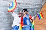 two humans waving PRIDE flags