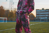 Man standing on a soccer field dressed in a 2010s Athleisure outfit, AI generated image, created with Midjourney.