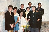 Group picture of eight people in room with writing all over the walls.