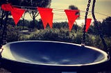 Red flags mark prohibited entry to a playground. A large bowl swing hangs from chains.