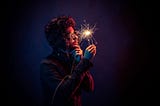 In the dark, man inspects a sparkler in his hand