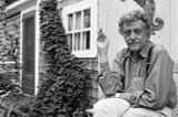 Kurt Vonnegut fumando à direita, ao lado de uma porta e uma trepadeira