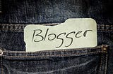 Jeans pocket with a paper sticking out that says, “blogger”.
