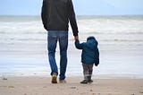 Photo of father with son walking on the beach; posted on Mickey D Markoff 2021 article on gratitude for sons; Photo by Szilvia Basso on Unsplash