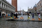 People walk on a catwalk in the flooded St. Mark’s Square, Venice