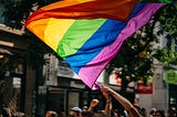 Pride flag being waved with two hands during a parade