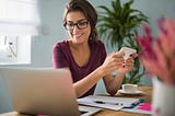 A smiling writer sits in front of her laptop with a sense of achievement.