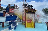 Pirate-themed waterpark attraction with a slides and a giant bucket dumping water down on kids.