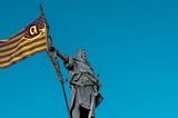 “Statue of a medieval knight raising a flag with modern corporate symbols: an ‘a’ with an arrow, set against a blue sky, symbolizing technocapitalism.”