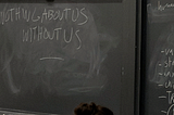 Partially erased chalkboard with the phrase “Nothing about us without us”